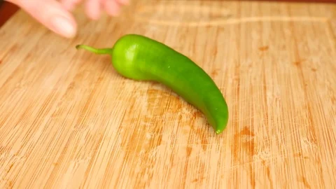 Female hands with a knife cut out hot pepper on a wooden board. 4k. Slow motion Stock Footage