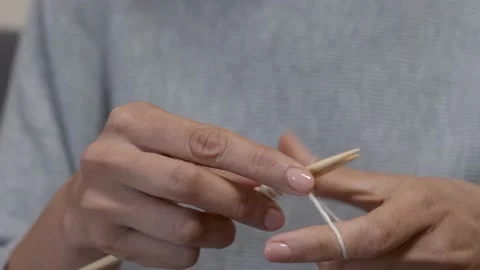 Female hands knits with wool threads and bamboo wooden needles on sofa at home Stock Footage 209961952