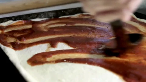 Female hands with a large spoon put sauce on the dough, a close plan Stock Footage 102709189