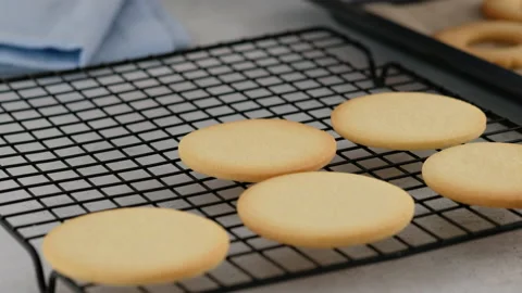 Female hands layout hot oven-baked cookies on the wire rack. Female hands a Stock Footage 145363679