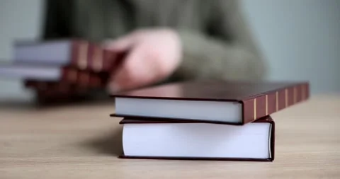 Female hands lays a stack of books on the table, a close-up Stock Footage 239240864
