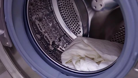 Female hands loading white clothes into washing machine drum to wash close up Video stock 264092891