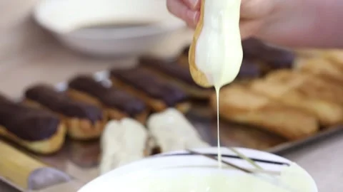 Female hands make eclairs with chocolate and white icing, close-up, slow motion Stock Footage 276364181