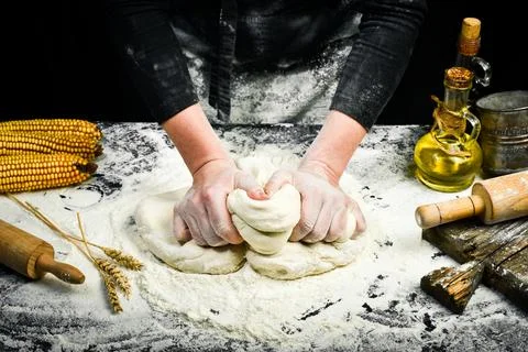Female hands making dough for bread with flour splash. Cooking background. Stock Photos