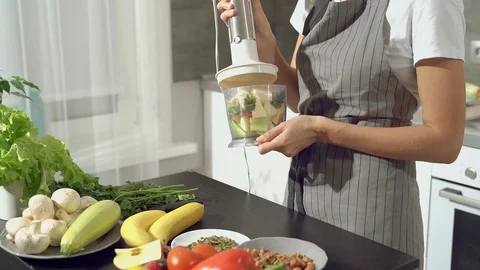 Female hands making fresh fruit smoothie using a blender in the kitchen Stock Footage 129599043