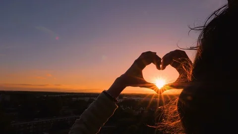 Female hands making heart shape gesture holding sun Stock Footage 77127730