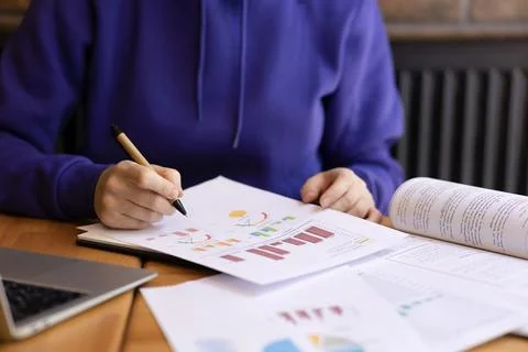 Female hands making notes on sheets with graphs and data with pen. Stock Photos