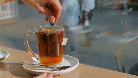 Female hands making tea, cup of tea on table in cafe Stock Footage