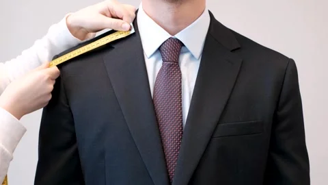 Female hands measure jacket with centimeter tape on gray background, front view. Stock Footage 303114936