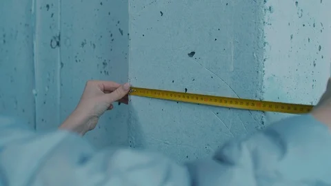 Female Hands Measuring Basement Wall with Tape Видео 101368675