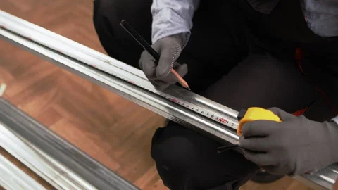 Female hands measuring length pressing a metal tape measure on textured metal Stock Footage 330358916
