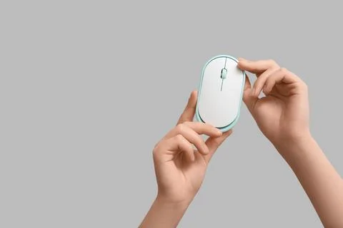 Female hands with modern wireless computer mouse on grey background Stock Photos