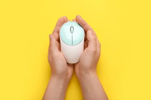Female hands with modern wireless computer mouse on yellow background Stock Photos