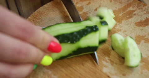 Female hands with multi-colored manicure cut cucumbers for salad Stock Footage 133830456