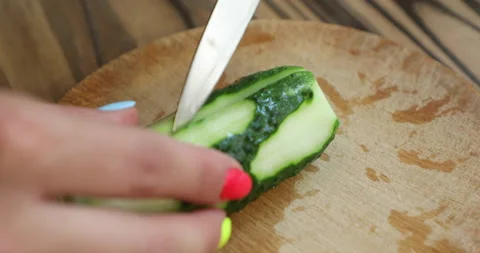 Female hands with multi-colored manicure cut cucumbers for salad Stock Footage 133831493
