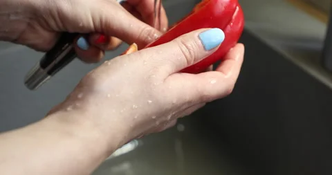 Female hands with multi-colored manicure wash and peel red bell pepper Stock Footage 133834200