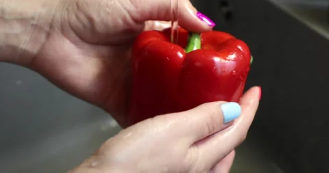 Female hands with multi-colored manicure wash red bell pepper Stock Footage 133834456