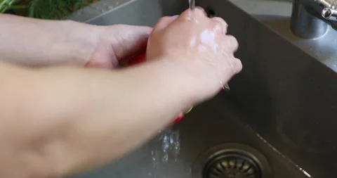 Female hands with multi-colored manicure wash red bell pepper Stock Footage 133835561