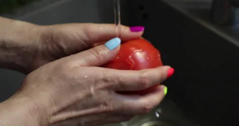 Female hands with multi-colored nails wash tomatoes Video stock 133835572