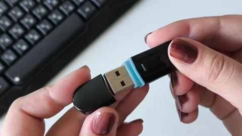 Female hands open the cap of a flash drive, in the background of a laptop Stock Footage 320523554