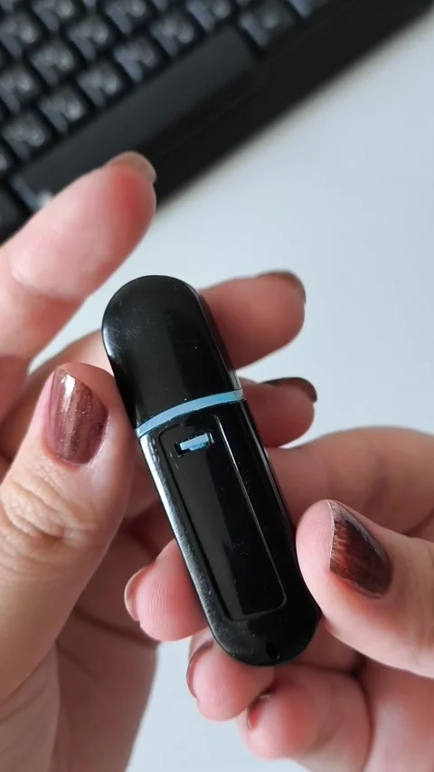 Female hands open the cap of a flash drive, in the background of a laptop Stock Footage 320523642