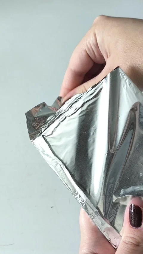Female hands opening a package of chocolate foil. Dark chocolate in foil Vidéo 330156719