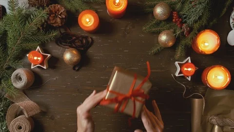 Female hands pack a box with a gift on a wooden Christmas background. Stock Footage 120202736