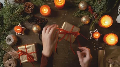 Female hands pack a box with a gift on a wooden Christmas background. Stock Footage 120203036