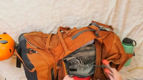 Female hands packing hiking backpack in top view timelapse, placing compact Stock Footage 334945801