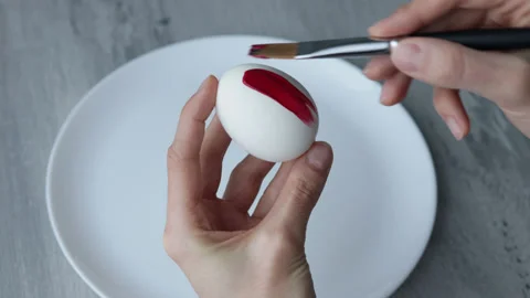 Female hands paint Easter egg in a modern minimalist style with red paint. Stock Footage 180415047