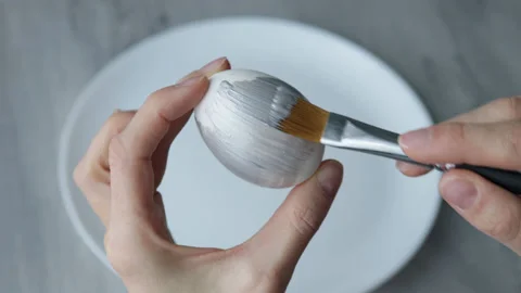 Female hands paint Easter egg in a modern minimalist style with silver paint. Stock Footage 180416228