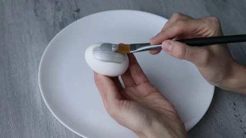 Female hands paint Easter egg in a modern minimalist style with silver paint. Video stock 180416261