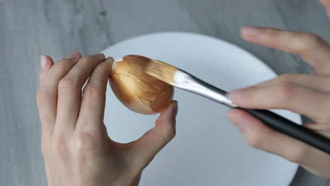 Female hands paint Easter egg in a modern minimalist style with gold paint. Stock Footage 180416805