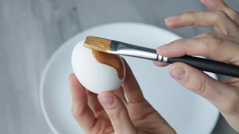 Female hands paint Easter egg in a modern minimalist style with gold paint. Stock Footage 180416966