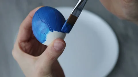 Female hands paint Easter egg in a modern minimalist style with blue paint. Stock Footage 180417618