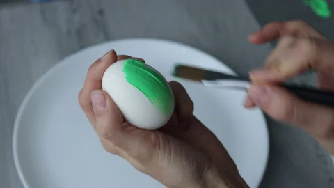 Female hands paint Easter egg in a modern minimalist style with green paint. Stock Footage 180418060
