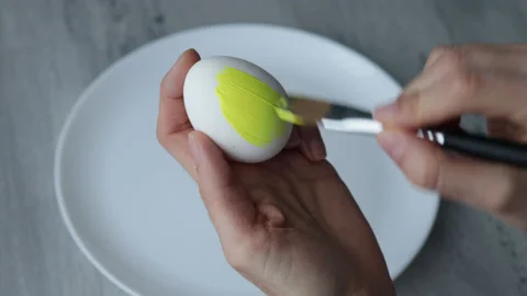 Female hands paint Easter egg in a modern minimalist style with yellow paint. Stock Footage 180418261