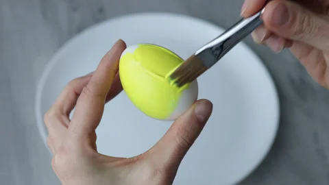 Female hands paint Easter egg in a modern minimalist style with yellow paint. Stock Footage 180418881