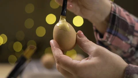 Female hands painting eggs using brush with gold paint. Easter, tradition and Stock Footage 329090286