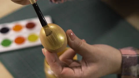 Female hands painting eggs using brush with gold paint. Easter, tradition and Stock Footage 329090311