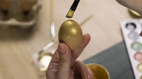 Female hands painting eggs using brush with gold paint. Easter, tradition and Stock Footage 329090380