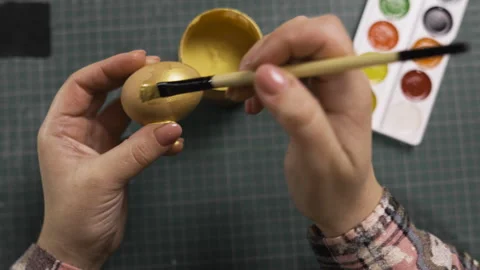 Female hands painting eggs using brush with gold paint. Easter, tradition and Stock Footage 329090464