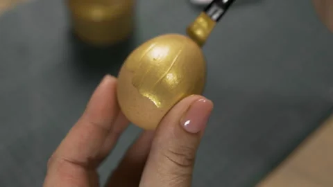 Female hands painting eggs using brush with gold paint. Easter, tradition and Stock Footage 329090504