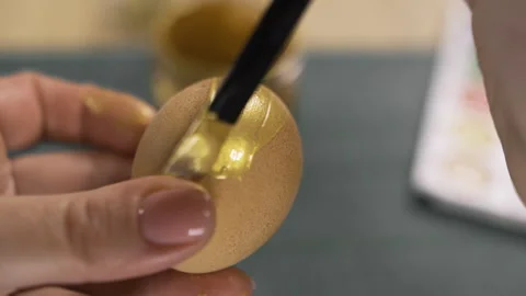 Female hands painting eggs using brush with gold paint. Easter, tradition and Stock Footage 329090531