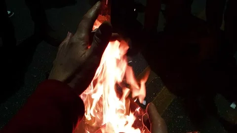 Female hands playing with the flames of a bonfire in the street. Stock Footage 313310741
