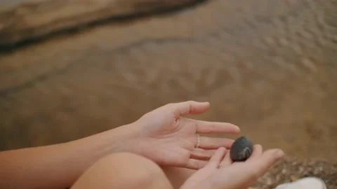 Female hands playing pebble stone over sea water ripple surface top view closeup Stock Footage 224970512