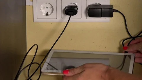 Female hands plug tablet computer and smart phone to wall socket charger Stock Footage 81960877
