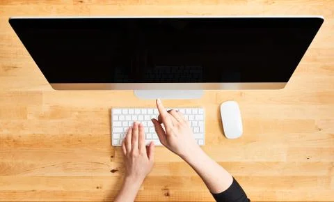 Female hands pointing at desktop computer. Stock Photos