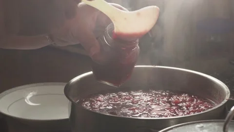 Female hands pour raspberry jam into canning jar from saucepan. Keeping Healthy Stock Footage 136123739