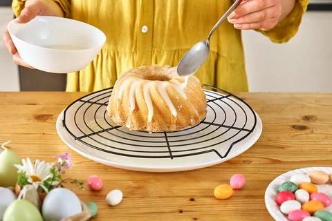 Female hands pouring icing on Easter cake. Traditional easter cake or sweet.. Stock Photos